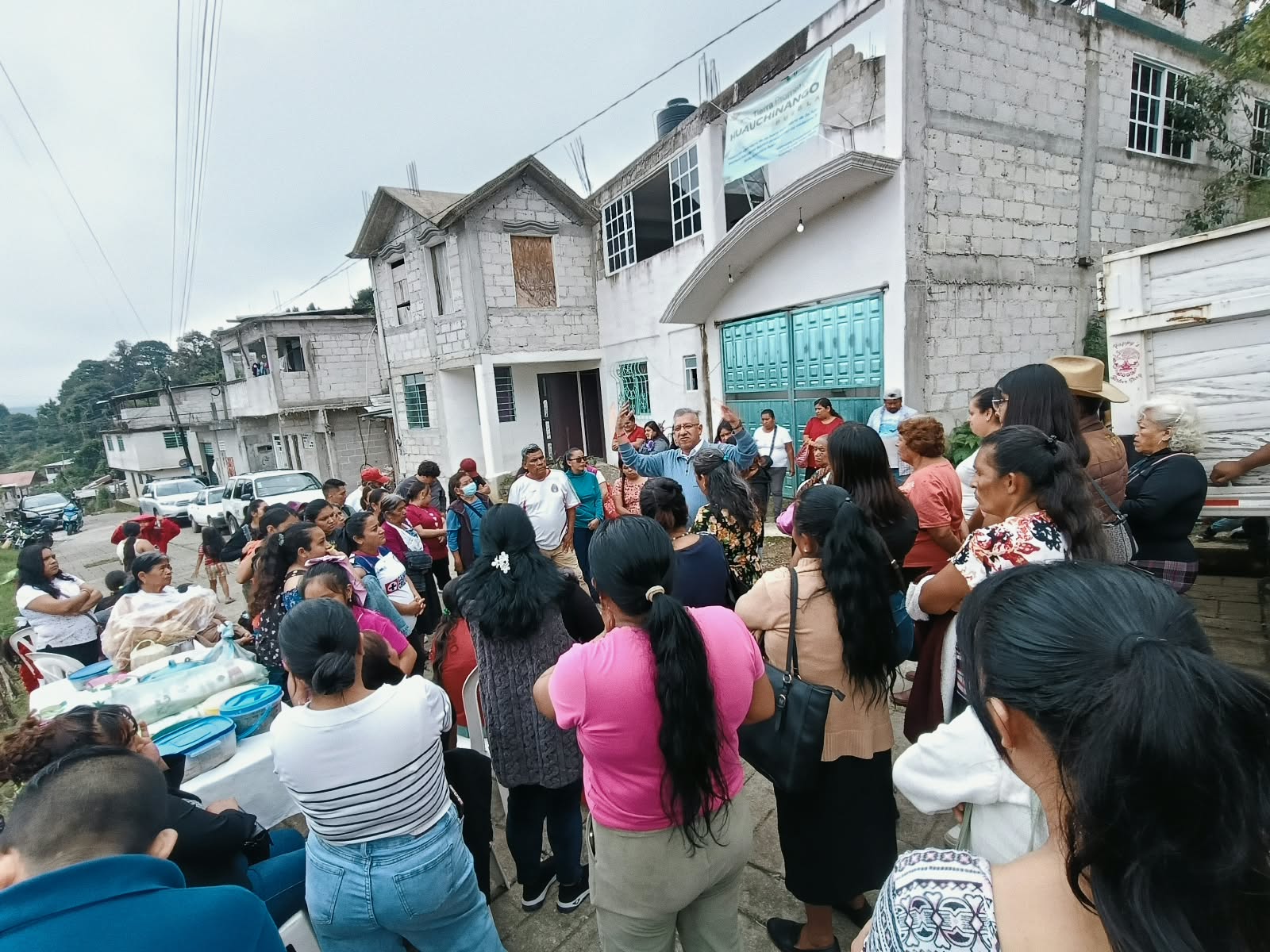 Un hombre habla con vecinas y vecinos reunidos en una colonia de Huauchinango.